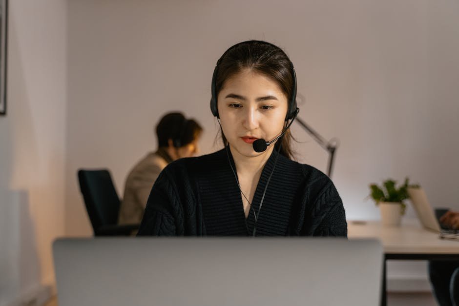 Professional call center agent in headphones diligently working on a computer indoors.